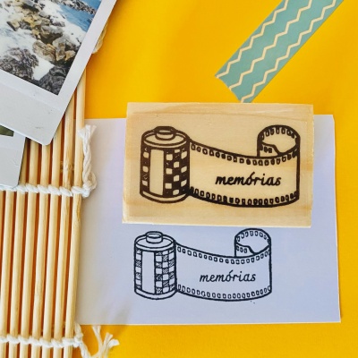 Carimbo de madeira com desenho de rolo de filme e palavra memórias