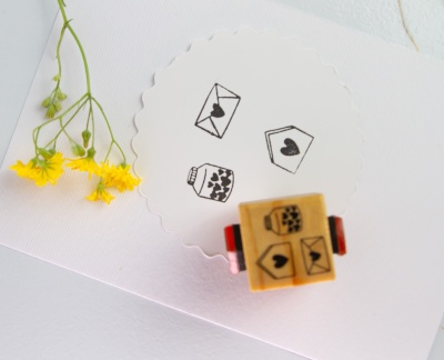 Selo de borracha com desenhos de carimbos, papel branco e flores amarelas