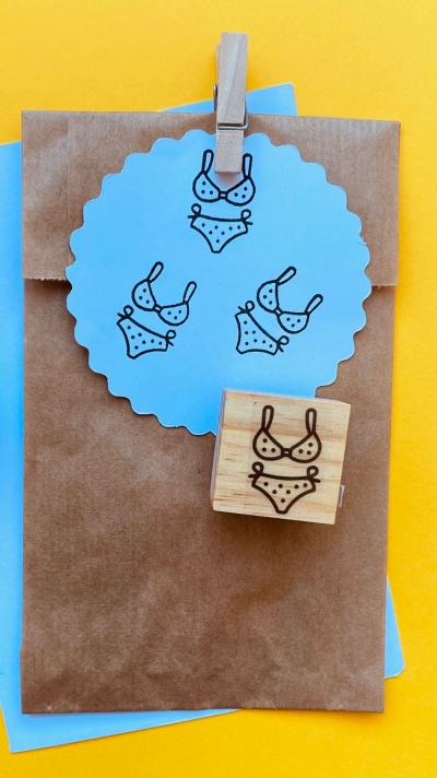 Carimbo de madeira com desenho de fato-de-banho e impressões em papel azul