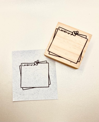 Carimbo de madeira com desenho de papéis e palavra 'Lembrar' e impressão em papel