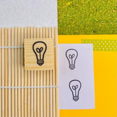 Bloco de madeira com desenho de lâmpada e papel com desenhos semelhantes sobre tapete de varetas