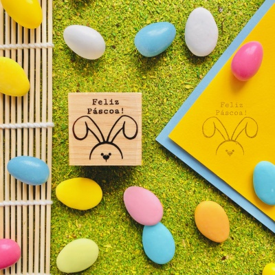 Carimbo e cartões de Páscoa com coelho e ovos coloridos sobre relva artificial