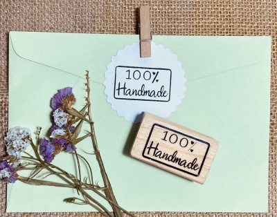 Envelope verde-claro com flores secas e selo com texto '100% Handmade'