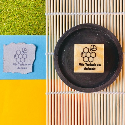 Sabonete com selo 'Não Testado em Animais' em prato preto sobre esteira de bambu