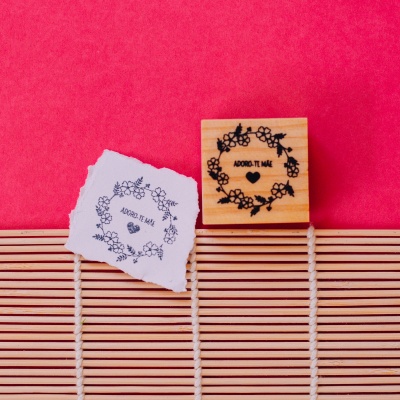 Carimbo de madeira com desenho floral e texto em papel