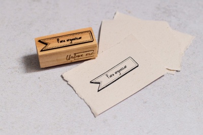 Carimbo de madeira com texto e folhas de papel com impressão