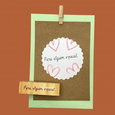Carimbo de madeira com a frase 'Para alguém especial' e cartão decorativo com corações