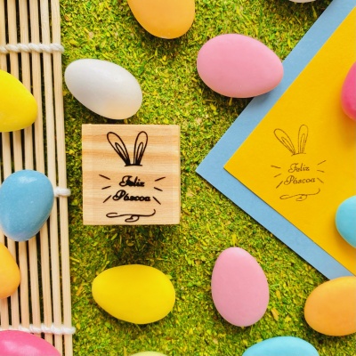 Carimbos de madeira com desenho de coelho e ovos coloridos sobre relva artificial