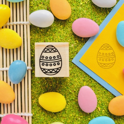 Carimbo de ovo de Páscoa decorado e ovos coloridos sobre superfície verde