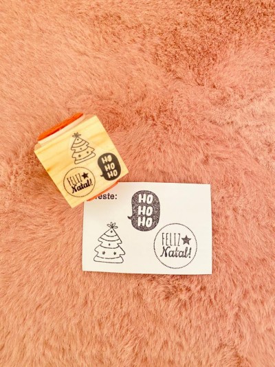 Carimbo de madeira com padrão Natal e cartão com mesmas estampas sobre tecido rosa claro