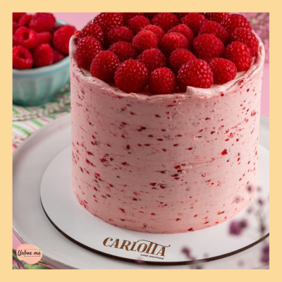 Bolo de framboesa com cobertura rosa e framboesas frescas no topo