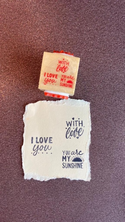 Carimbo de madeira com tinta vermelha e papel com texto carimbado a preto