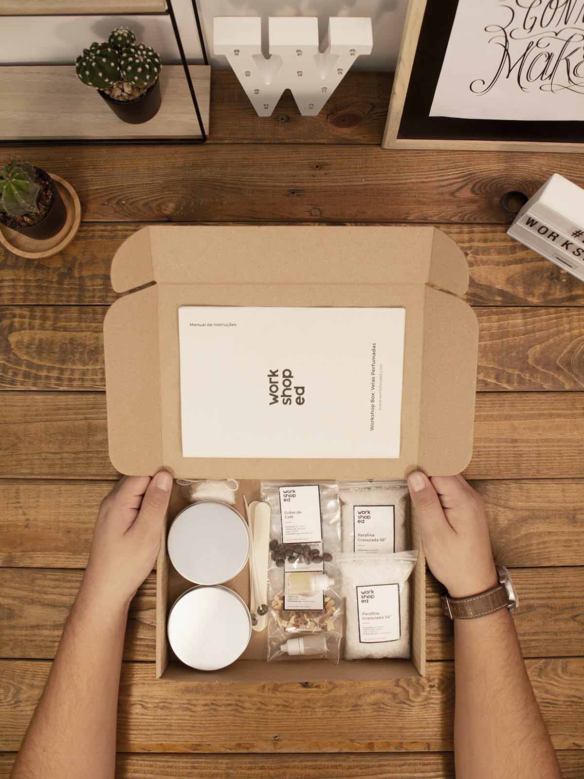 Workshop Box: Velas Aromáticas Conjunto de produtos para workshop em caixa de cartão sobre mesa de madeira com plantas e objetos decorativos