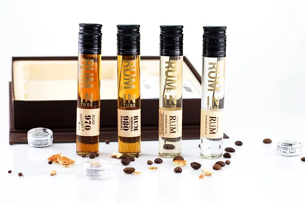 À Descoberta do Rum Português Quatro frascos estreitos de rum com tampas pretas, etiquetas e grãos de café à volta