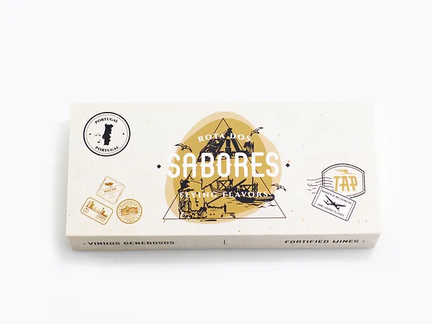 Rota dos Sabores/Vinhos Generosos Embalagem branca de produto Saboress com ilustração amarela e preta e vários selos decorativos em fundo branco