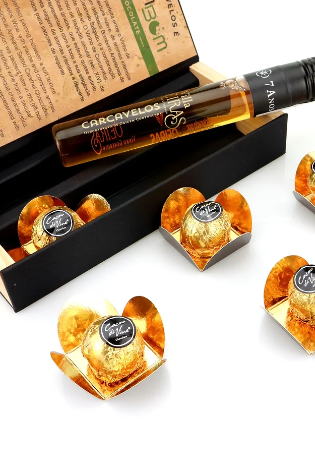 Carcavelos é BomBom garrafa pequena com líquido âmbar e chocolates embrulhados em papel dourado