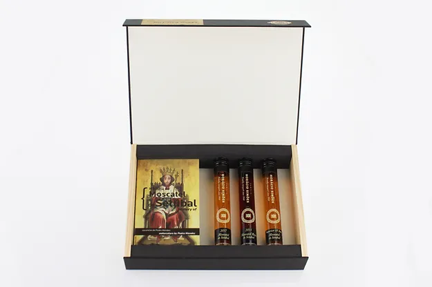 Bebendo a História do Moscatel de Setúbal Caixa preta aberta com tubos de ensaio e folheto, fundo branco