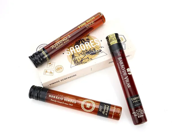 Rota dos Sabores/Vinhos Generosos Três tubos com líquidos castanho escuro sobre embalagem branca com texto SABORES