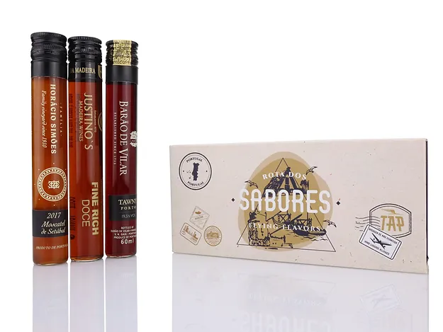 Rota dos Sabores/Vinhos Generosos Três garrafas de vidro pequenas com líquidos coloridos e uma caixa branca ao lado