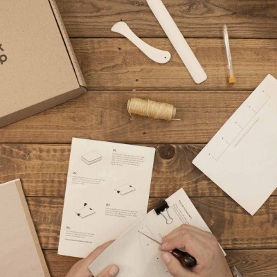 Kit de costura com caixa de cartão, ferramentas e instruções sobre mesa de madeira