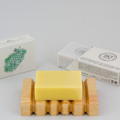 Sabonete amarelo quadrado em saboneteira de madeira com caixas brancas ao fundo
