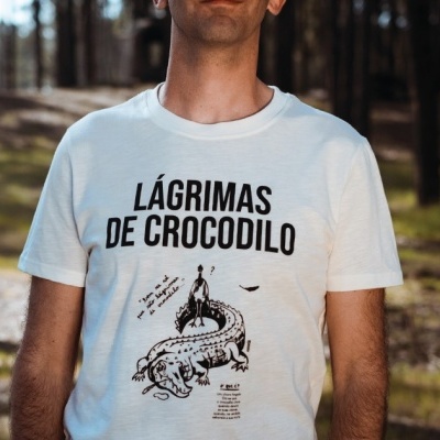 Homem com t-shirt branca com texto e ilustração de crocodilo em floresta