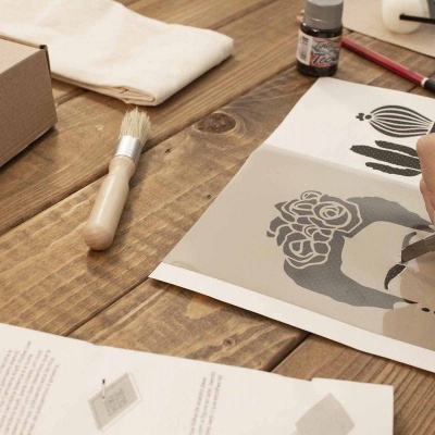 Mesa de madeira com desenho a tinta preta de mão com flores, pincel e frasco de tinta