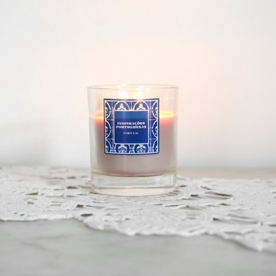 Vela perfumada branca em copo de vidro com etiqueta azul em toalha rendada branca