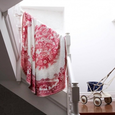Cobertor vermelho e branco pendurado em escada, carrinho de bebé vintage ao lado