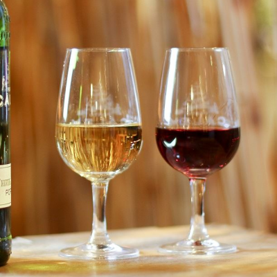 Garrafas e taças de vinho em superfície de madeira com fundo desfocado