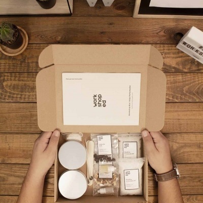 Conjunto de produtos para workshop em caixa de cartão sobre mesa de madeira com plantas e objetos decorativos