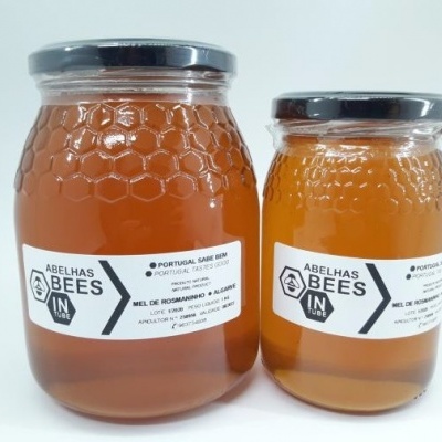 Dois frascos de vidro com tampa metálica preta de mel com padrão hexagonal e rótulos brancos