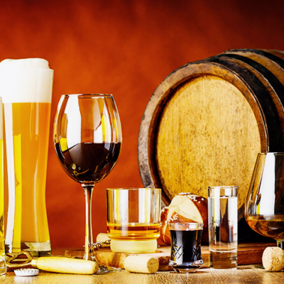 Copos com várias bebidas alcoólicas e barris de madeira ao fundo