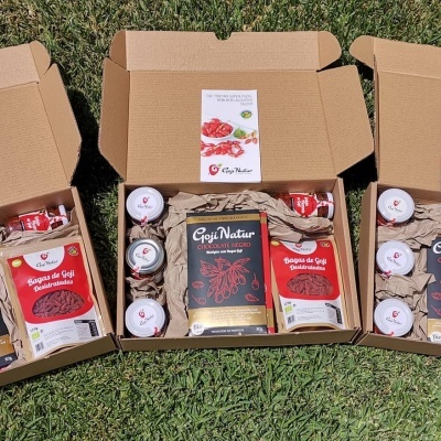 Três caixas abertas com produtos Goji Natur sobre relva