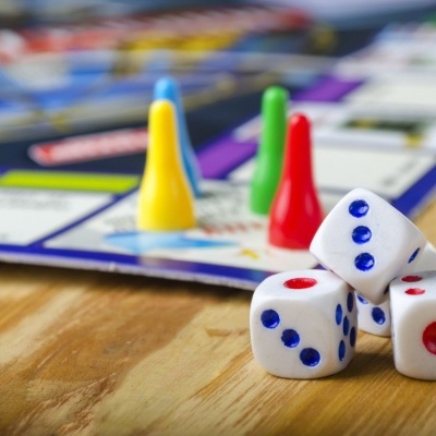 Peças coloridas e dados de jogo de tabuleiro sobre mesa de madeira