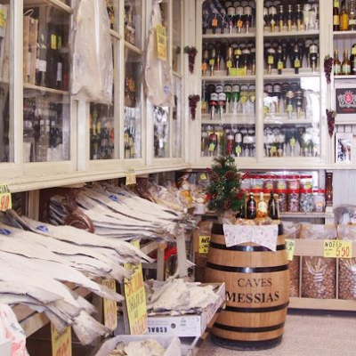 Interior de loja tradicional com bebidas, peixe seco e barril de madeira