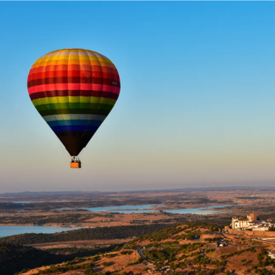 Balão de ar quente colorido voando sobre paisagem rural