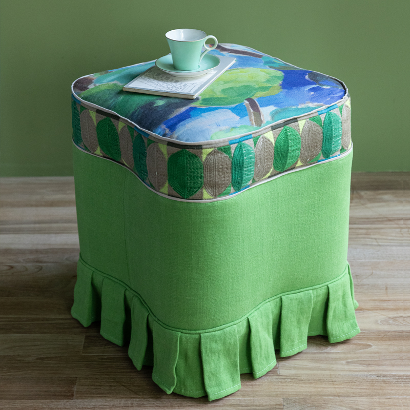 Pufe quadrado verde com almofada estampada de folhas e chávena verde em cima