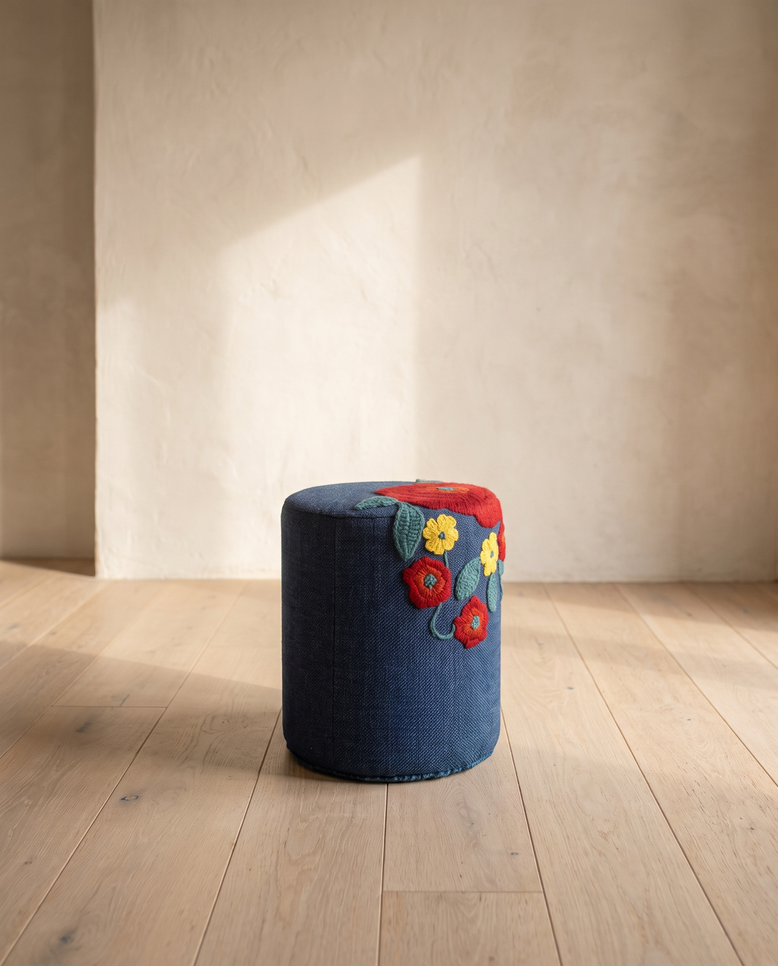 Pufe cilíndrico azul com bordados florais coloridos