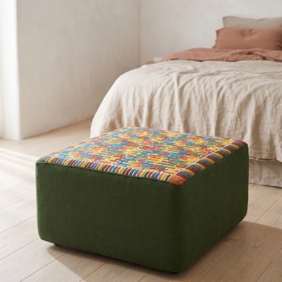 Pufe quadrado verde com topo estampado colorido em chão de madeira clara