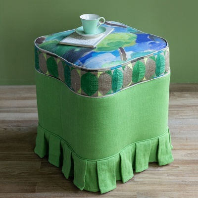 Pufe quadrado verde com almofada estampada de folhas e chávena verde em cima