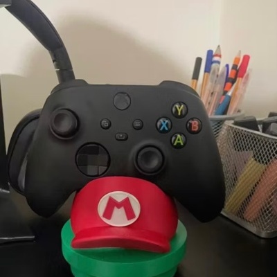 Comando preto com botões coloridos sobre suporte vermelho e verde, com canetas ao lado