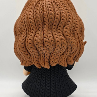 Figura de brinquedo com cabelo castanho e casaco preto vista de costas