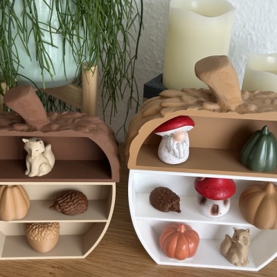 Duas prateleiras decorativas em forma de meia noz com figuras de esquilos, cogumelos, ouriços e abóboras em madeira, planta e velas ao fundo.