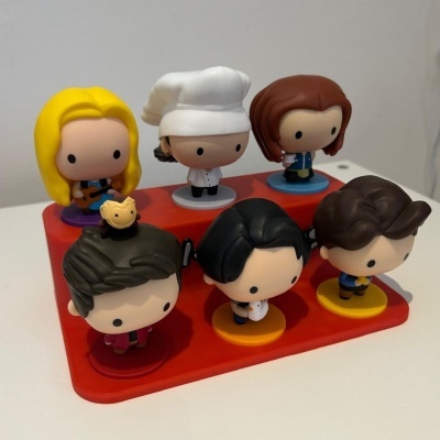 Seis figuras de brinquedo estilizadas em plástico sobre base vermelha em degraus