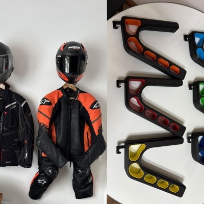 Fatos de moto com capacetes pendurados na parede e suportes para capacetes coloridos em mesa branca