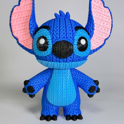 Boneco azul de tricot da personagem Stitch com grandes orelhas cor de rosa e pretos nas patas