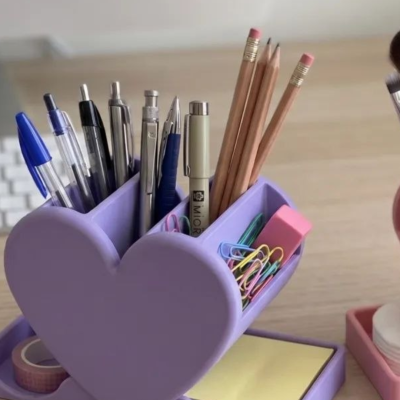 Organizador de secretária lilás em forma de coração com material de escrita e acessórios de escritório.