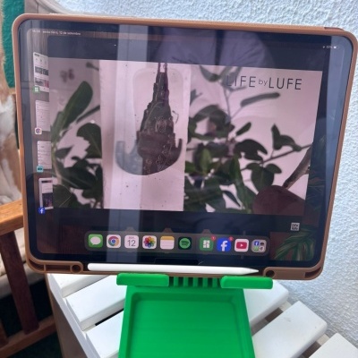 Tablet com capa castanha e suporte verde numa mesa branca mostrando LIFE by LUFE