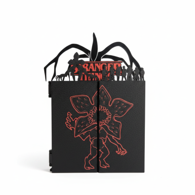 Livro preto com ilustração vermelha de monstro e recortes na capa